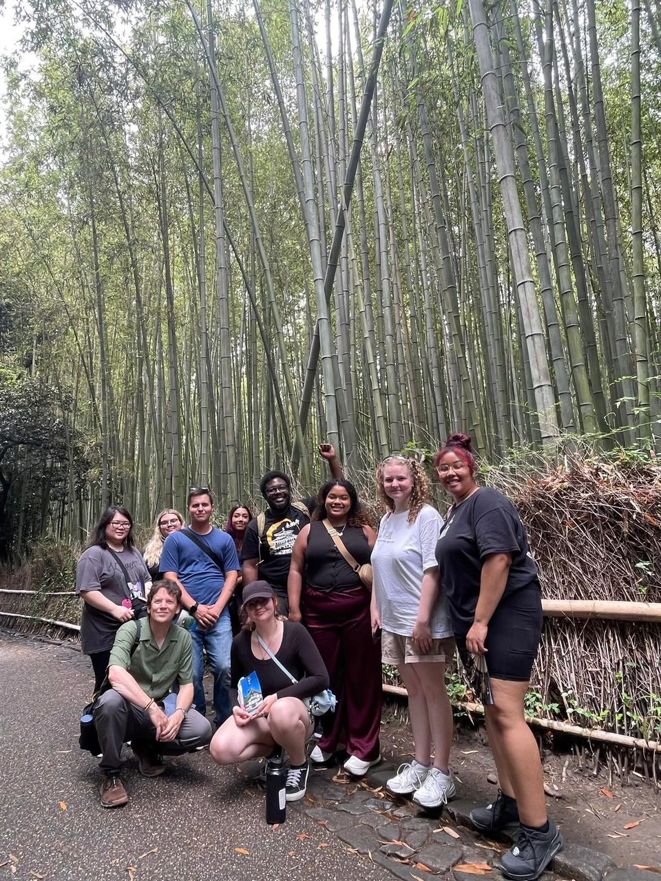 A group of students and their professor posing in front of bamboo trees somewhere in Japan.